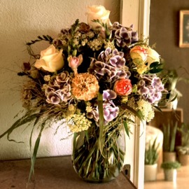 Arrangement de fleurs coupées dans un vase transparent avec Lysianthus, jacinthes, ail, anémones et roses «David Austin».
